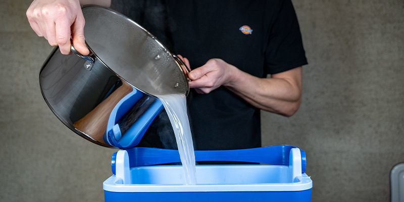 Zodra het water is gekookt en je het gips hebt toegevoegd, giet je het over de kokosvezel en vermiculiet in de emmer